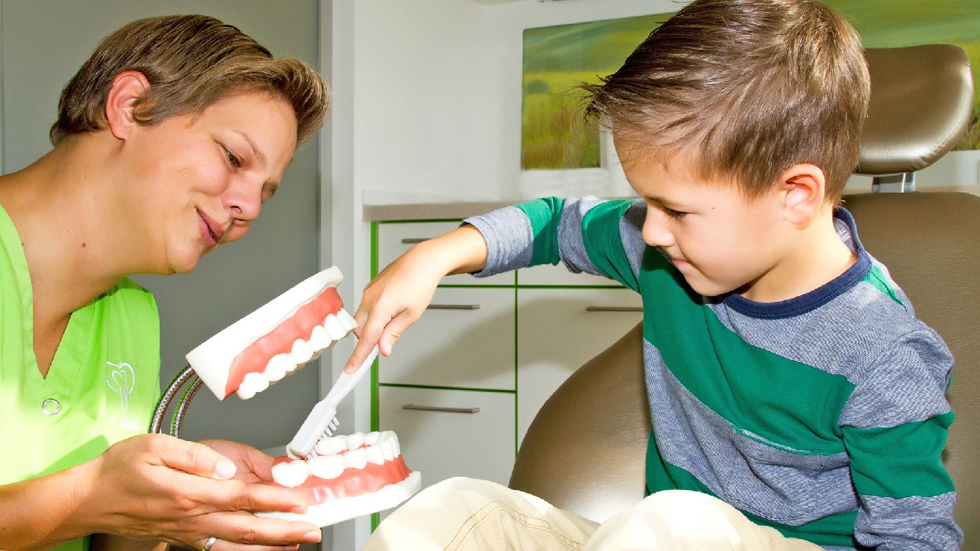 Claudia Schüller erklärt einem jungen Patienten die richtige Zahnpflege